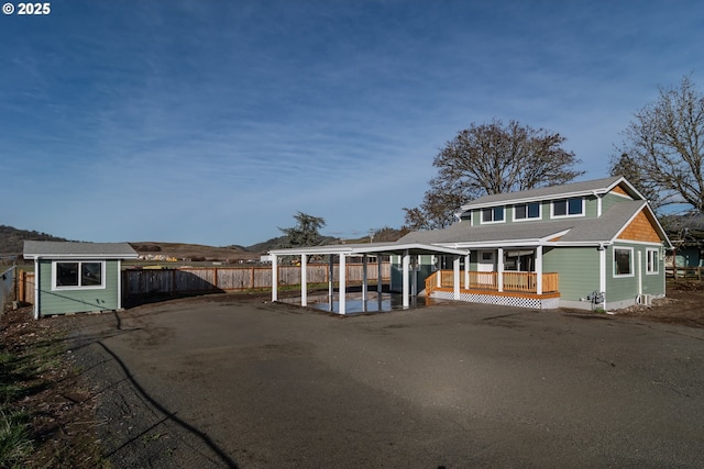 view of front of home with an outbuilding, aphalt driveway, fence, a wooden deck, and a shed