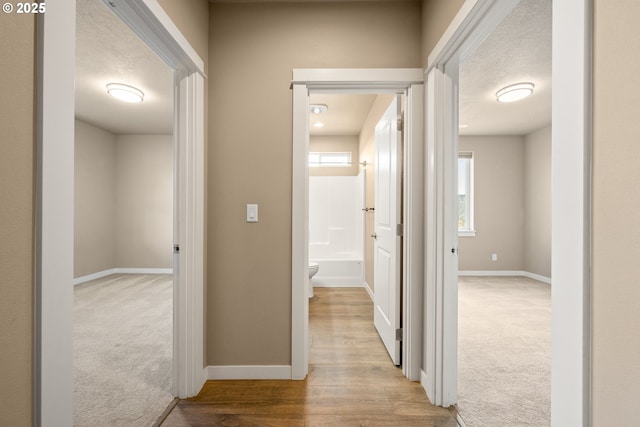 7220 SE Night Hawk Ct, Prineville, OR 97754 - hall featuring a textured ceiling, carpet floors, wood finished floors, and baseboards