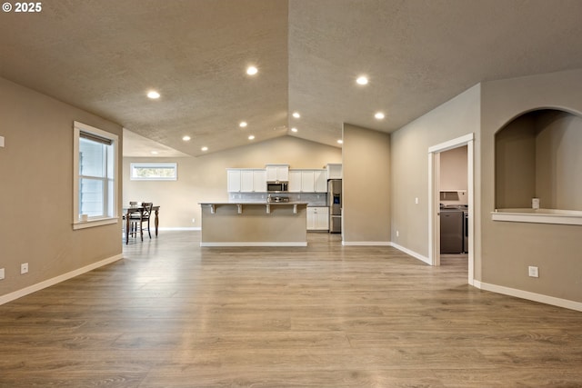 7220 SE Night Hawk Ct, Prineville, OR 97754 - unfurnished living room featuring vaulted ceiling, recessed lighting, baseboards, and light wood-style floors