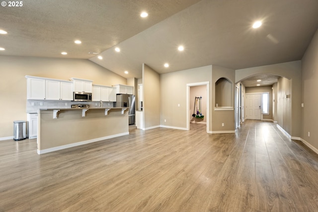 7220 SE Night Hawk Ct, Prineville, OR 97754 - kitchen with a breakfast bar area, appliances with stainless steel finishes, light wood-style floors, open floor plan, and white cabinetry