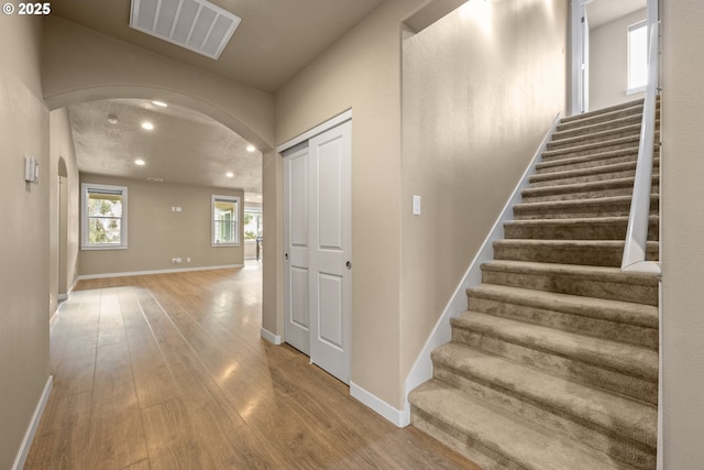 7220 SE Night Hawk Ct, Prineville, OR 97754 - staircase featuring baseboards, visible vents, arched walkways, and wood finished floors