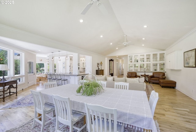 dining space with ceiling fan, crown molding, lofted ceiling, and light wood-type flooring