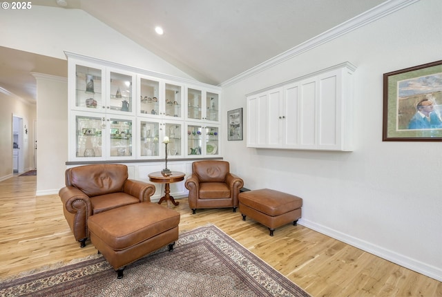 living area with light hardwood / wood-style floors, ornamental molding, and vaulted ceiling