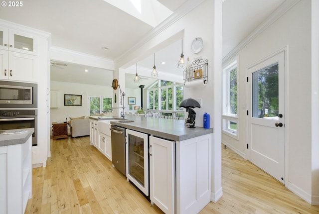 kitchen with white cabinets, beverage cooler, appliances with stainless steel finishes, and hanging light fixtures