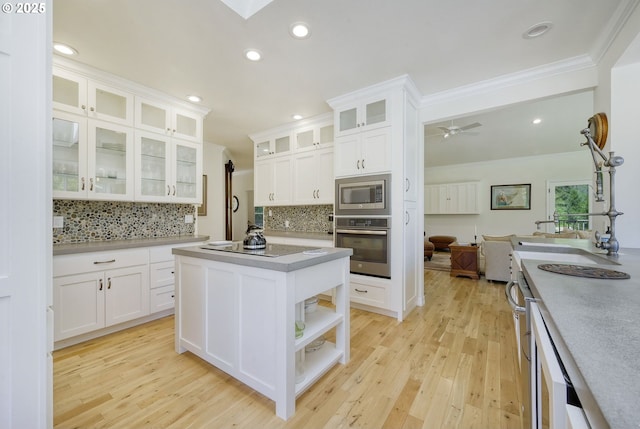 kitchen with white cabinetry, light wood-type flooring, a kitchen island, backsplash, and stainless steel appliances