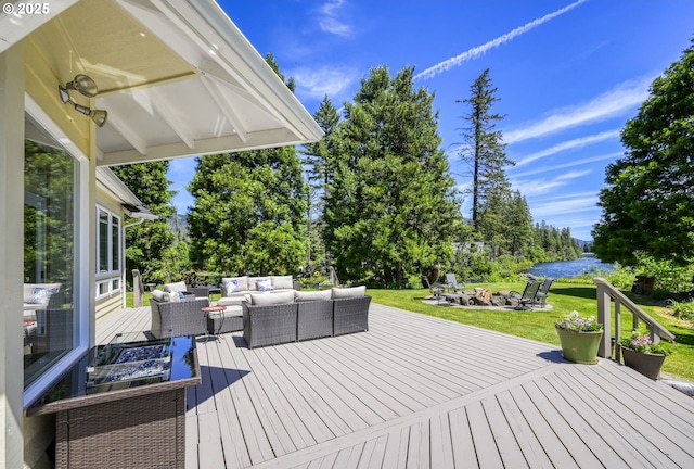 wooden deck with a yard, a water view, and an outdoor living space with a fire pit