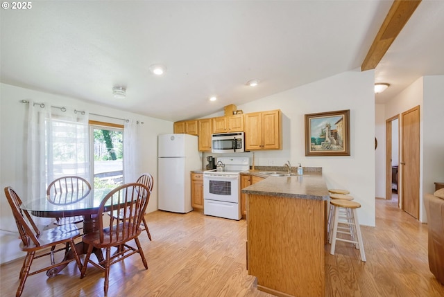 kitchen featuring kitchen peninsula, light hardwood / wood-style flooring, sink, white appliances, and a kitchen bar