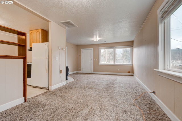 unfurnished living room featuring light colored carpet and a textured ceiling