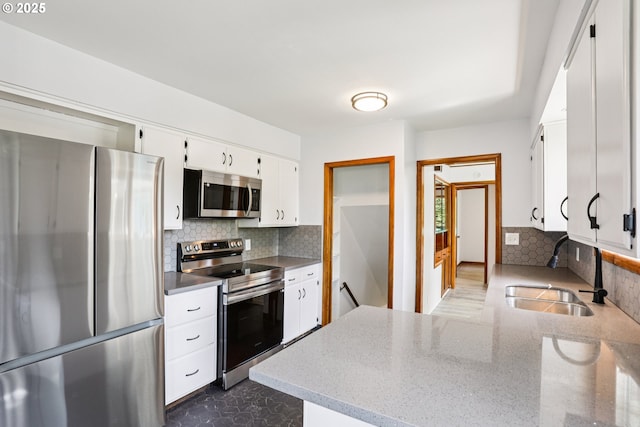 10925 NE Skidmore St, Portland, OR 97220 - kitchen featuring stainless steel appliances, backsplash, white cabinetry, a peninsula, and light stone counters