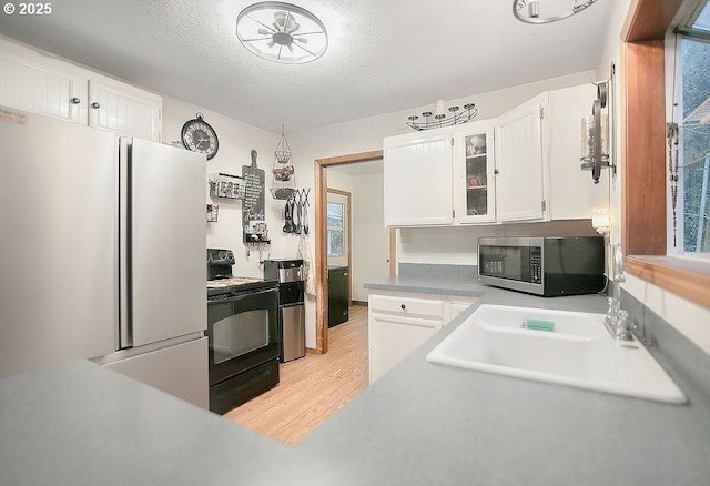 kitchen with white cabinets, white refrigerator, light hardwood / wood-style flooring, a textured ceiling, and black range with electric cooktop