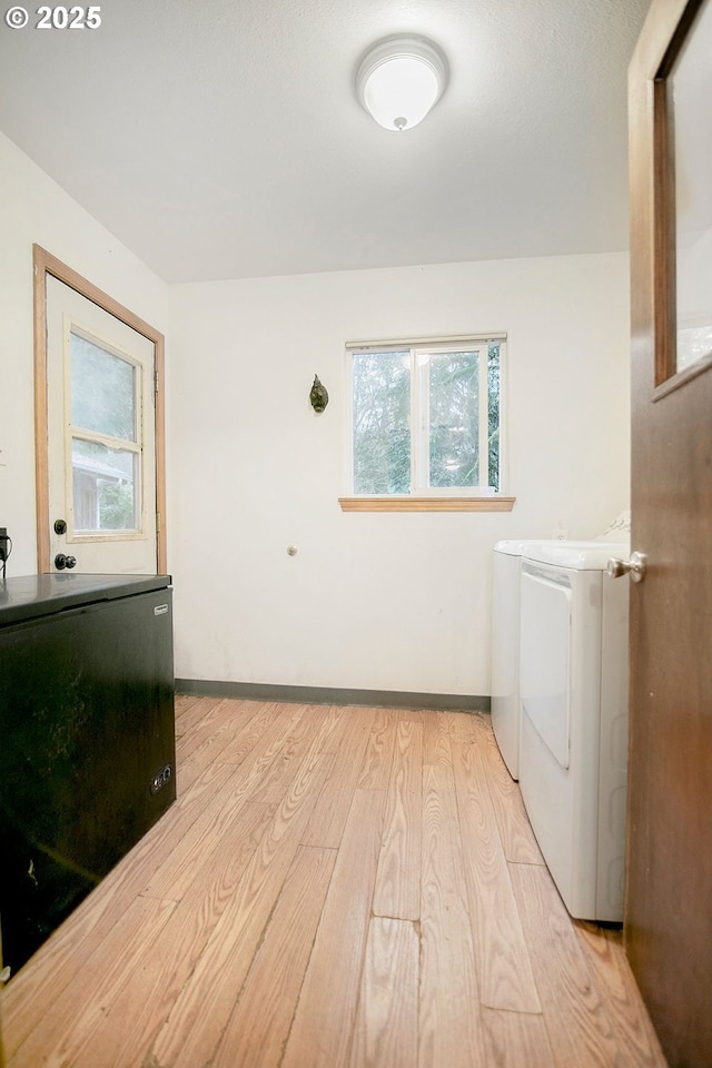 clothes washing area featuring washer and clothes dryer and light hardwood / wood-style floors