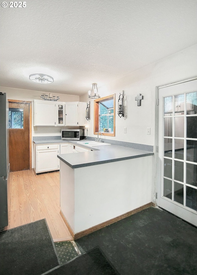 kitchen featuring white cabinets, sink, a textured ceiling, appliances with stainless steel finishes, and kitchen peninsula