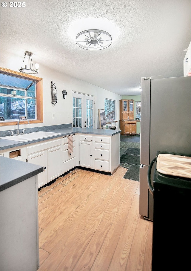 kitchen with french doors, electric stove, sink, light hardwood / wood-style floors, and white cabinetry