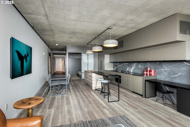 1410 NW Kearney St Unit 721, Portland, OR 97209 - kitchen with dark countertops, pendant lighting, light wood finished floors, backsplash, and visible vents