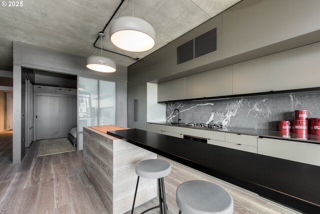 1410 NW Kearney St Unit 721, Portland, OR 97209 - bar featuring wood finished floors, a sink, decorative light fixtures, backsplash, and visible vents