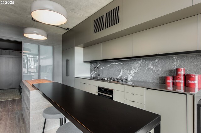1410 NW Kearney St Unit 721, Portland, OR 97209 - kitchen with oven, dark wood-style floors, a sink, stainless steel gas stovetop, and modern cabinets