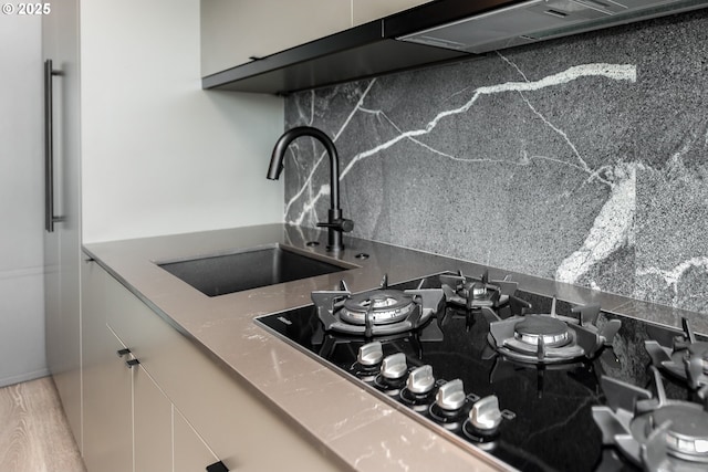 1410 NW Kearney St Unit 721, Portland, OR 97209 - kitchen featuring decorative backsplash, a sink, black gas stovetop, and white cabinets