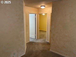 hallway with dark colored carpet