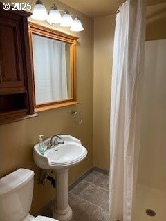 full bathroom featuring tile patterned flooring, toilet, a stall shower, and a sink
