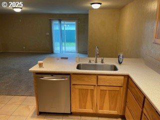 kitchen featuring a sink, light carpet, stainless steel dishwasher, and light countertops