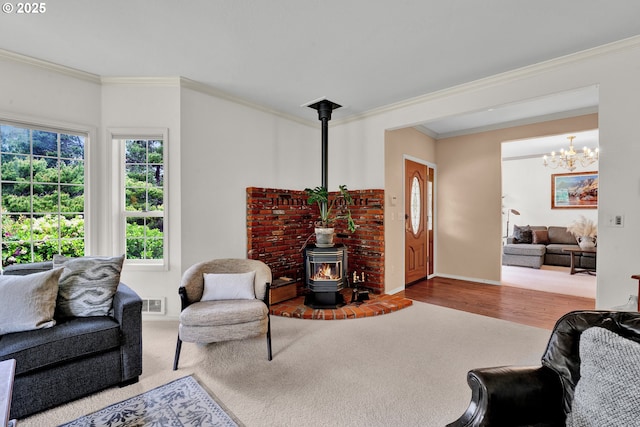 living room with a wood stove, ornamental molding, a chandelier, baseboards, and carpet floors