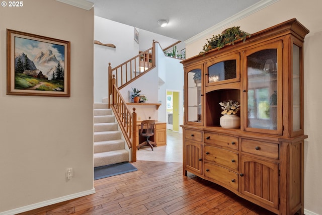 staircase featuring hardwood / wood-style flooring, baseboards, and ornamental molding