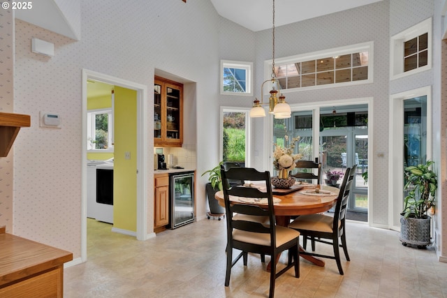dining space featuring beverage cooler, high vaulted ceiling, and baseboards