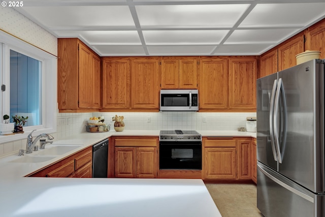 kitchen with stainless steel appliances, a sink, light countertops, decorative backsplash, and brown cabinets