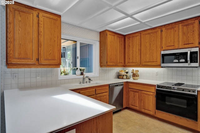 kitchen with stainless steel appliances, a sink, and brown cabinetry