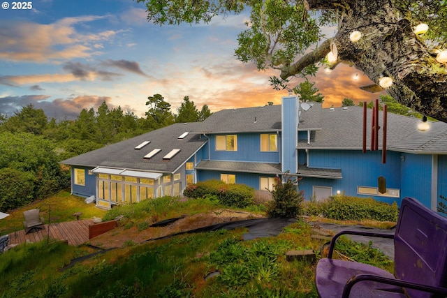 back of property featuring a chimney and roof with shingles