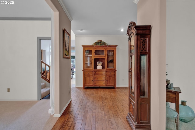 corridor featuring ornamental molding, stairs, light wood finished floors, and baseboards