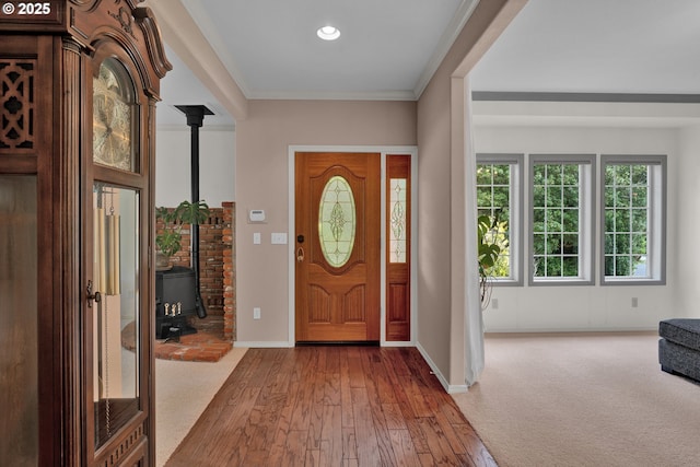 entrance foyer with a wood stove, wood-type flooring, baseboards, and crown molding