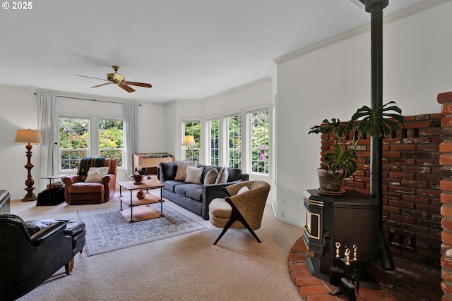 carpeted living room featuring a wood stove, ornamental molding, and a ceiling fan