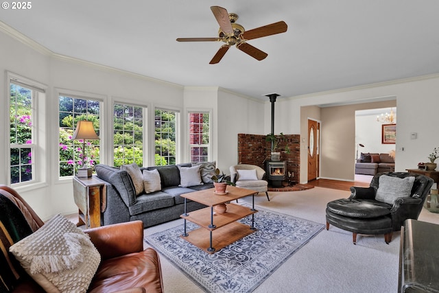 living room featuring a wood stove, crown molding, ceiling fan, wood finished floors, and a chandelier