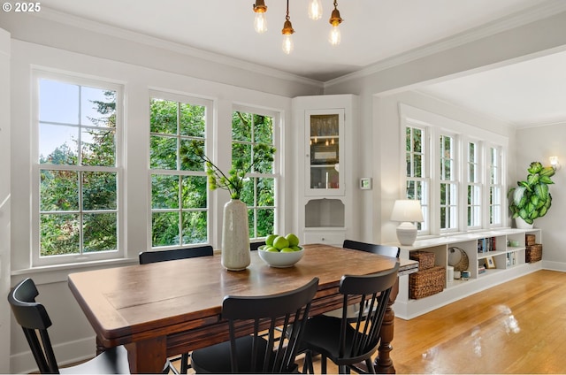 dining space featuring ornamental molding and light hardwood / wood-style flooring