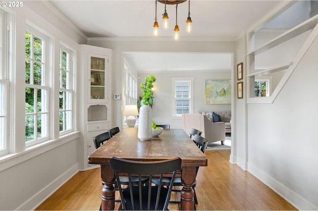 dining space featuring light wood-type flooring and crown molding