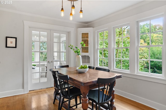 dining area with light wood-type flooring, french doors, and crown molding