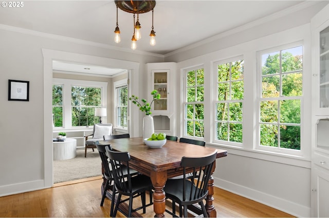 dining space with light wood-type flooring, a wealth of natural light, and ornamental molding