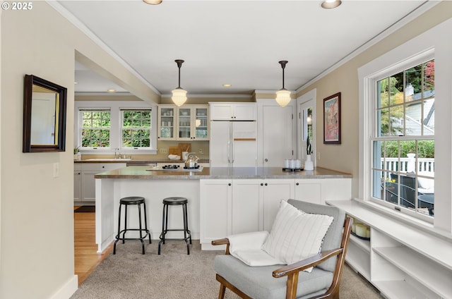 kitchen with white appliances, decorative light fixtures, white cabinetry, light carpet, and light stone counters