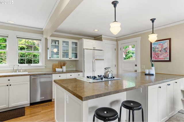 kitchen featuring pendant lighting, sink, white appliances, white cabinetry, and a kitchen breakfast bar