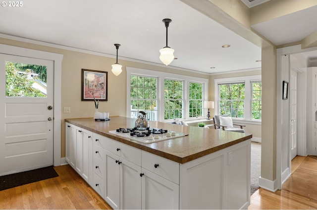 kitchen with white cabinets, decorative light fixtures, ornamental molding, white gas cooktop, and light hardwood / wood-style flooring