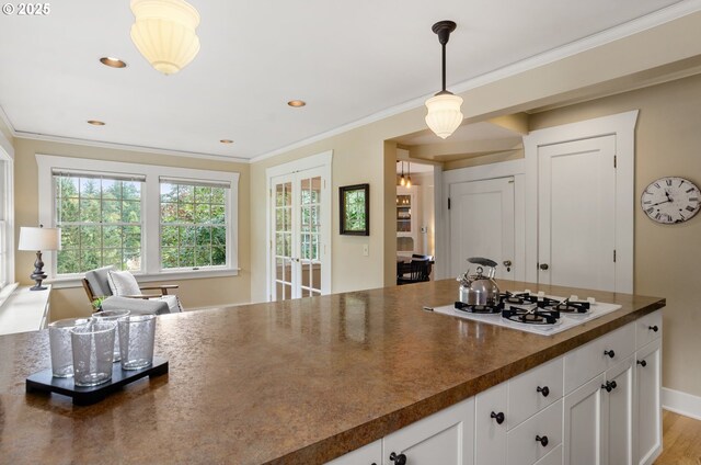 kitchen with white gas stovetop, white cabinetry, hanging light fixtures, hardwood / wood-style flooring, and crown molding