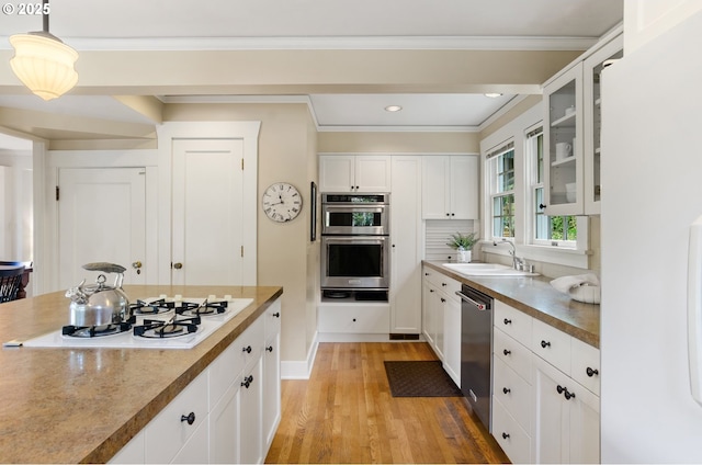 kitchen with light hardwood / wood-style floors, pendant lighting, sink, stainless steel appliances, and white cabinets