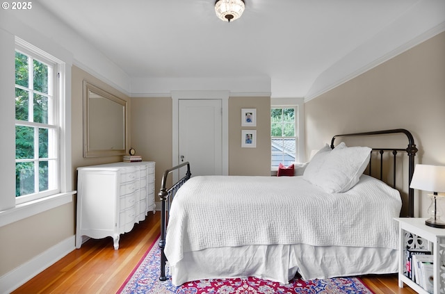 bedroom with multiple windows, wood-type flooring, and lofted ceiling