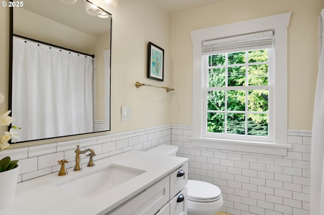 bathroom featuring tile walls, toilet, and vanity