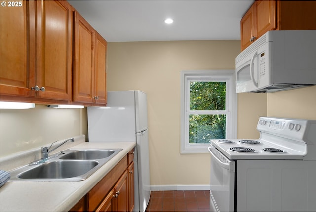 kitchen with dark tile patterned flooring, sink, and white appliances