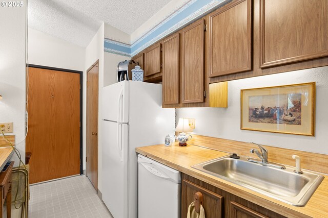 11044 SW Greenburg Rd Unit 321, Portland, OR 97223 - kitchen with white dishwasher, a sink, brown cabinetry, a textured ceiling, and wood counters