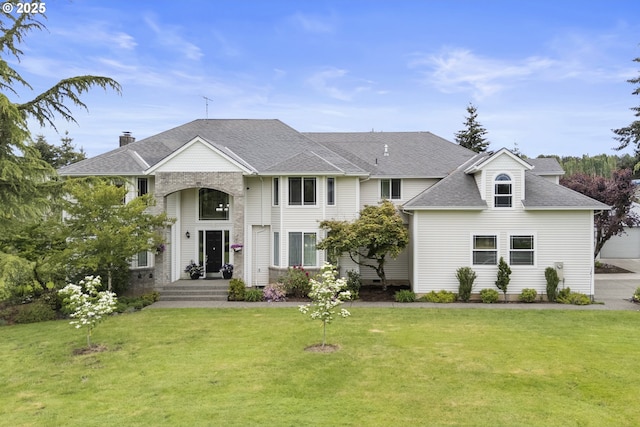 view of front of property featuring a front lawn and a shingled roof