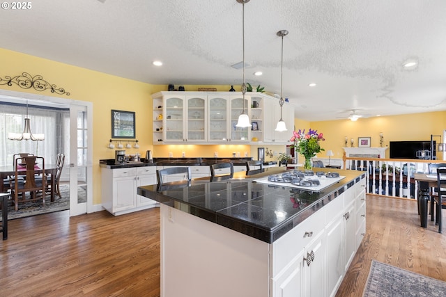 kitchen with white gas stovetop, wood finished floors, tile counters, a textured ceiling, and open shelves