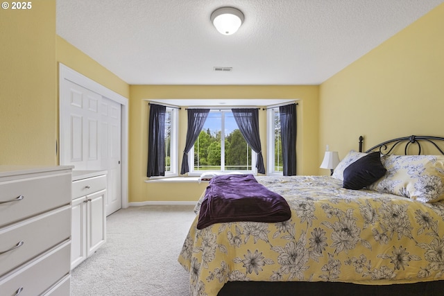 bedroom featuring light carpet, a textured ceiling, and baseboards